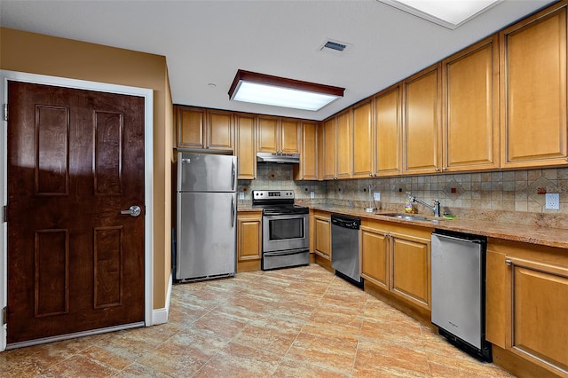 kitchen featuring visible vents, appliances with stainless steel finishes, a sink, under cabinet range hood, and backsplash