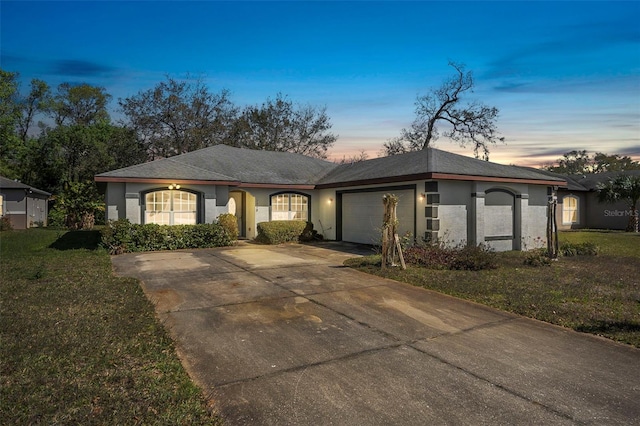 ranch-style house featuring a front yard, driveway, an attached garage, and stucco siding