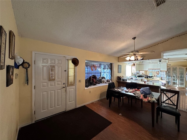 dining area featuring visible vents, a ceiling fan, wood finished floors, vaulted ceiling, and a textured ceiling