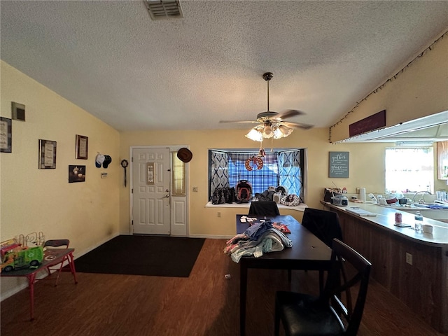 dining room with visible vents, lofted ceiling, ceiling fan, wood finished floors, and a textured ceiling