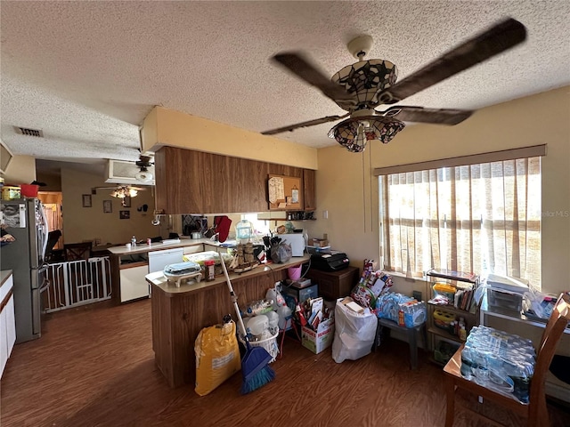 kitchen featuring dishwashing machine, brown cabinets, dark wood-style flooring, and freestanding refrigerator