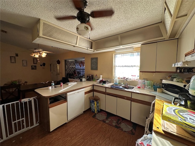 kitchen featuring a peninsula, dark wood-style flooring, white dishwasher, and light countertops