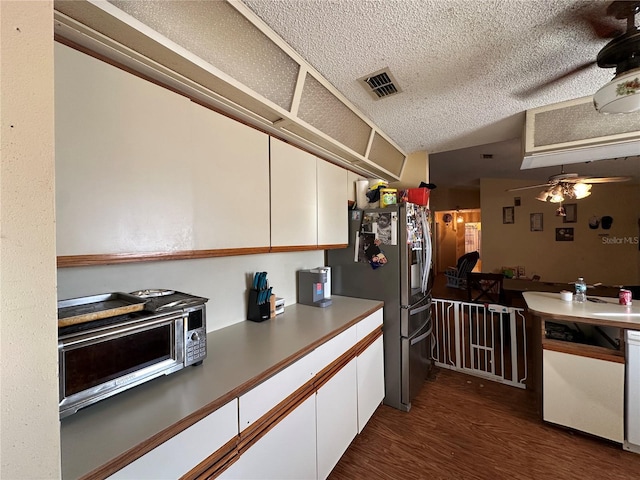 kitchen featuring dark wood-style flooring, visible vents, white cabinets, stainless steel fridge with ice dispenser, and dishwasher