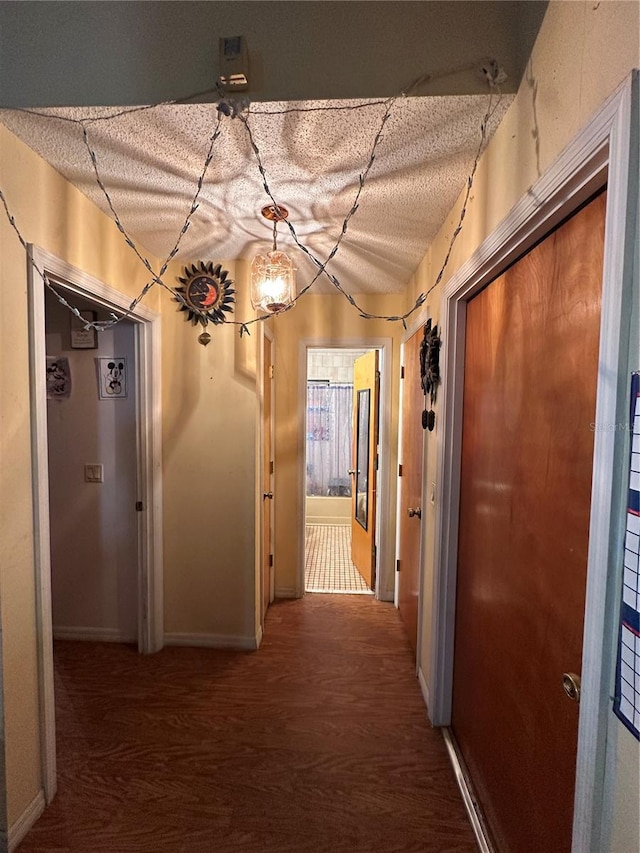 corridor featuring baseboards and a textured ceiling