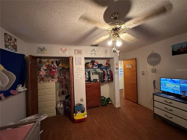 bedroom featuring ceiling fan, visible vents, dark wood finished floors, and a textured ceiling