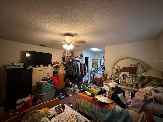 bedroom with a skylight, ceiling fan, and a textured ceiling