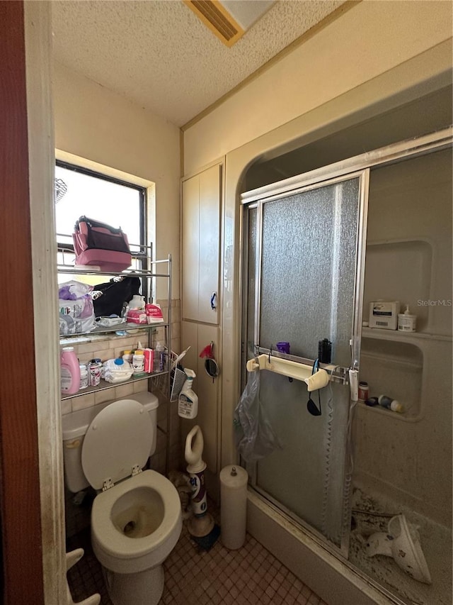 bathroom with toilet, tile patterned flooring, a shower stall, and a textured ceiling