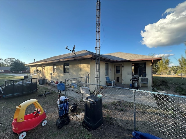 back of property with central AC unit, fence, and stucco siding