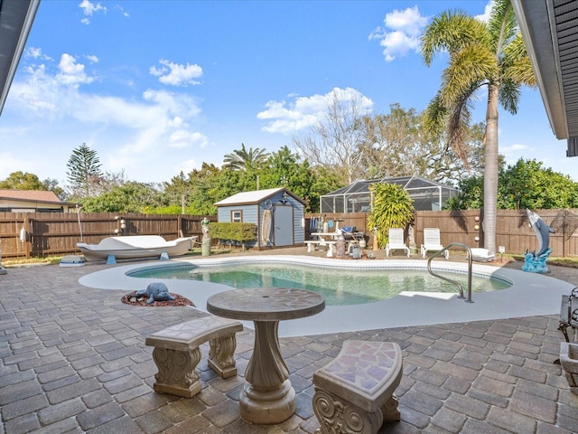 view of pool with an outbuilding, a storage unit, a fenced backyard, and a patio area