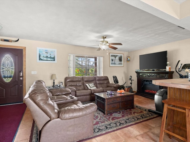 living area featuring a glass covered fireplace, a ceiling fan, and tile patterned flooring