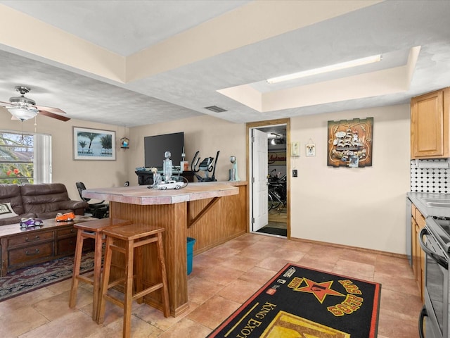 kitchen featuring a breakfast bar area, visible vents, a peninsula, stainless steel range with electric stovetop, and open floor plan