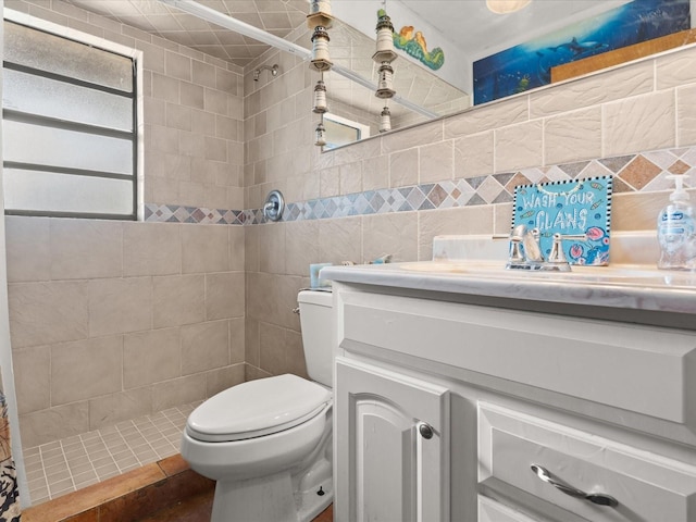 bathroom featuring tile walls, toilet, tiled shower, and vanity