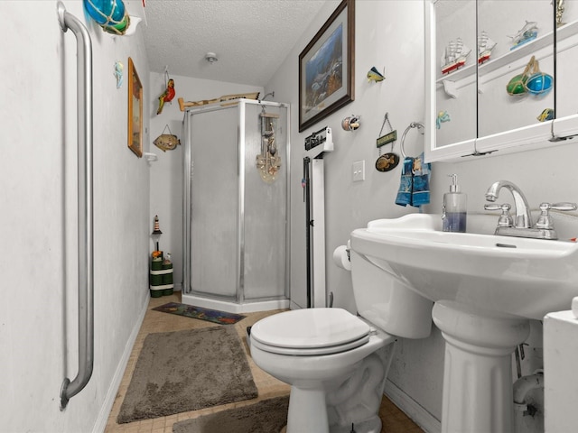 full bath featuring a shower stall, toilet, baseboards, and a textured ceiling