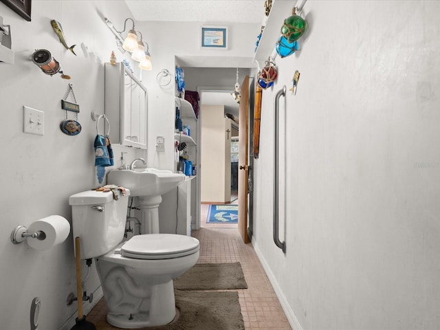 half bath featuring a textured ceiling, toilet, and baseboards