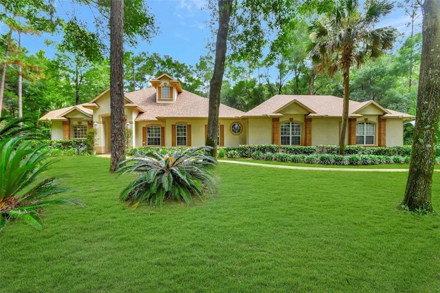 view of front of property with stucco siding, a front lawn, and roof with shingles