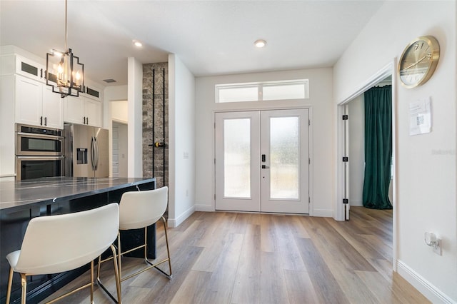 kitchen featuring stainless steel appliances, dark countertops, hanging light fixtures, glass insert cabinets, and white cabinets