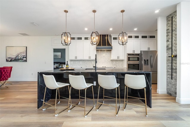 kitchen featuring appliances with stainless steel finishes, dark countertops, glass insert cabinets, and custom range hood