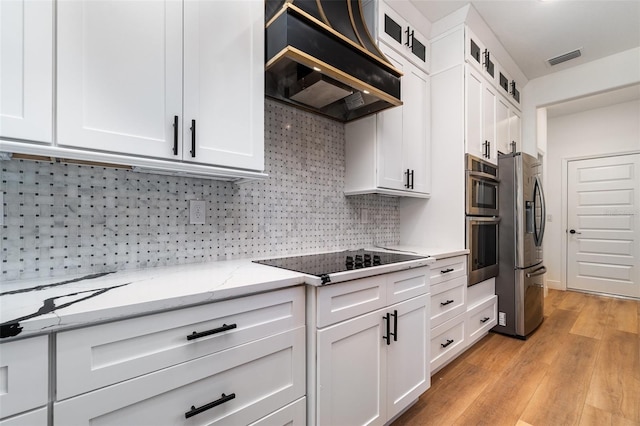 kitchen featuring visible vents, white cabinets, glass insert cabinets, appliances with stainless steel finishes, and custom exhaust hood