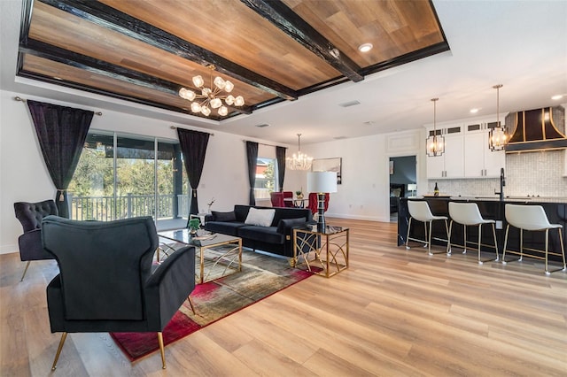 living area with light wood-style floors, a chandelier, and a tray ceiling