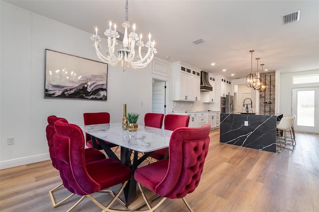 dining room featuring a chandelier, light wood-style flooring, visible vents, and baseboards