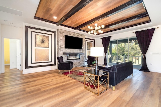 living room featuring a large fireplace, a tray ceiling, and wood finished floors