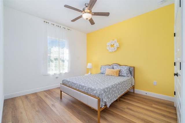 bedroom with a ceiling fan, baseboards, and wood finished floors