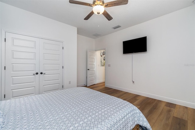 bedroom featuring baseboards, visible vents, ceiling fan, dark wood-style flooring, and a closet