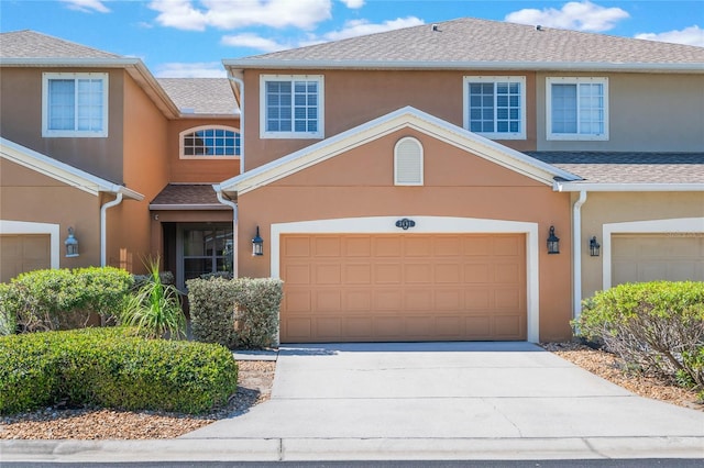 view of front of property with concrete driveway, stucco siding, a garage, and a shingled roof