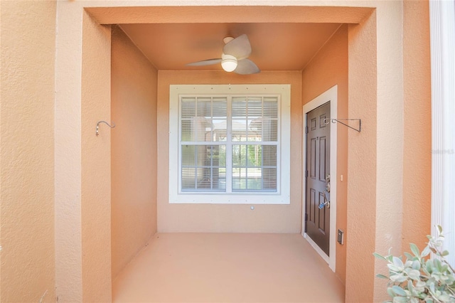 doorway to property featuring ceiling fan and stucco siding