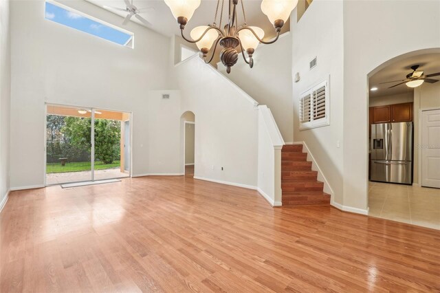 3691 Titanic Cir, Melbourne, FL 32903 - unfurnished living room featuring arched walkways, ceiling fan, stairs, a high ceiling, and light wood-style flooring