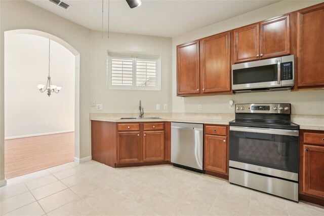 3691 Titanic Cir, Melbourne, FL 32903 - kitchen featuring stainless steel appliances, a sink, light countertops, a chandelier, and brown cabinetry