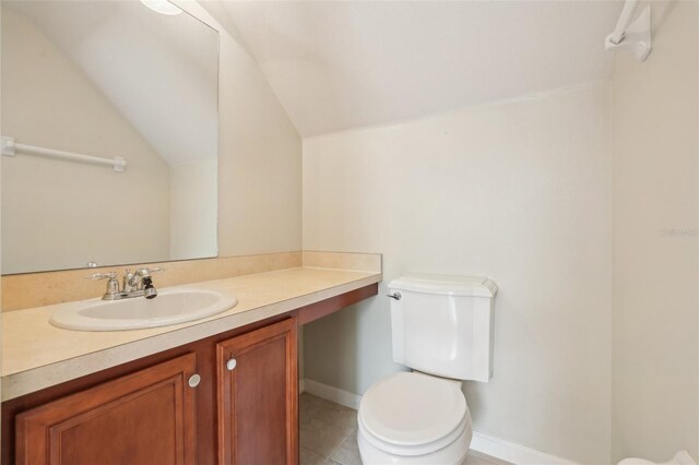 3691 Titanic Cir, Melbourne, FL 32903 - bathroom with toilet, vaulted ceiling, vanity, baseboards, and tile patterned flooring