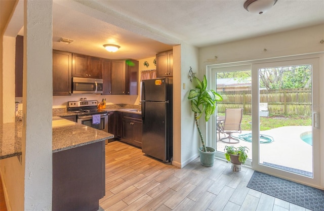 kitchen featuring wood finish floors, stainless steel appliances, visible vents, stone countertops, and baseboards