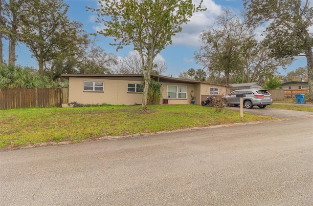 ranch-style home with driveway, a front yard, and fence