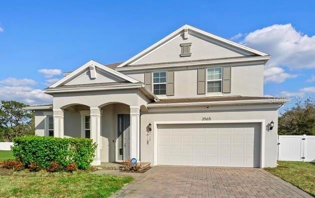 view of front of property with an attached garage, fence, decorative driveway, a gate, and stucco siding