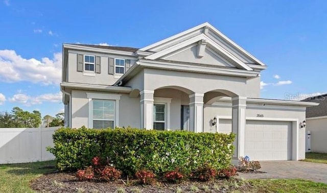 view of front facade featuring a garage, decorative driveway, fence, and stucco siding