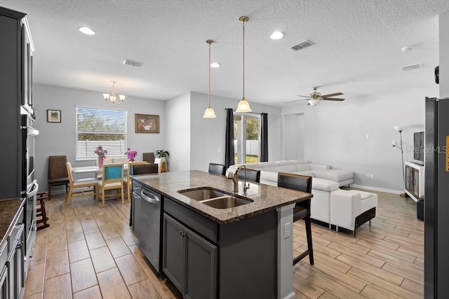 kitchen with wood finish floors, a breakfast bar, stainless steel appliances, visible vents, and a sink