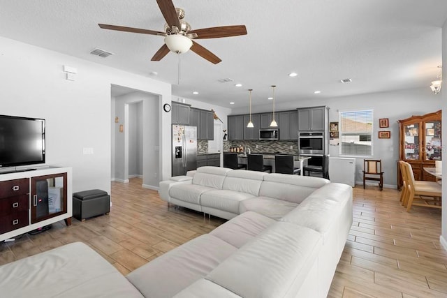 living area with baseboards, visible vents, a ceiling fan, wood finish floors, and recessed lighting