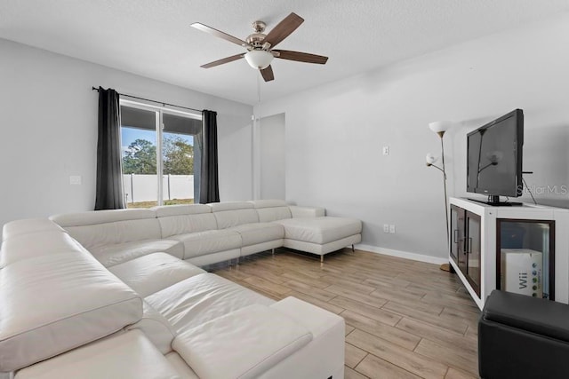 living room featuring baseboards, a textured ceiling, a ceiling fan, and wood tiled floor