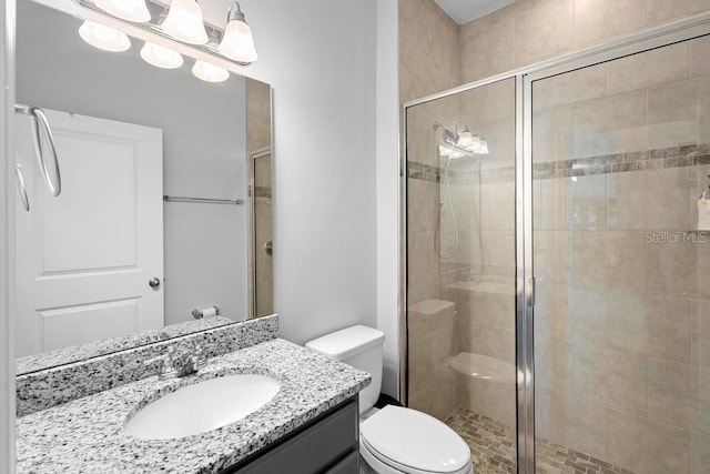 bathroom featuring a stall shower, vanity, and toilet