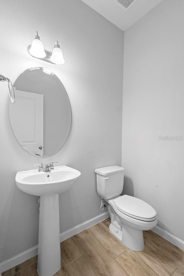 bathroom with wood finished floors, toilet, and baseboards