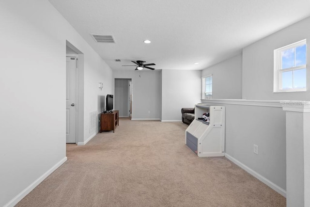 interior space featuring light carpet, a ceiling fan, visible vents, and baseboards