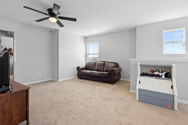 carpeted living room featuring ceiling fan, a textured ceiling, and baseboards