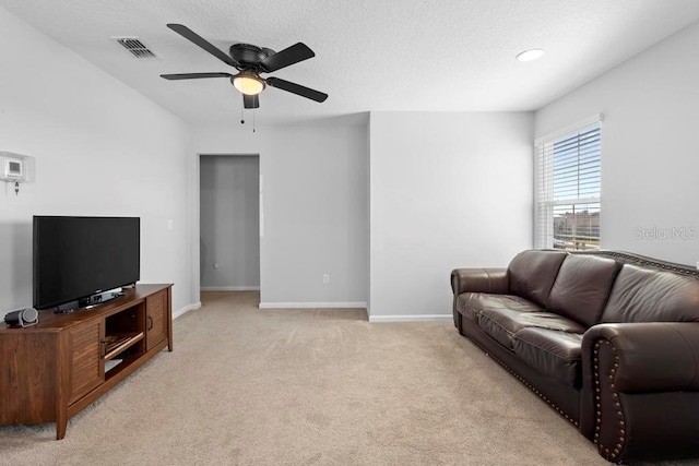 living area featuring baseboards, visible vents, light colored carpet, ceiling fan, and a textured ceiling