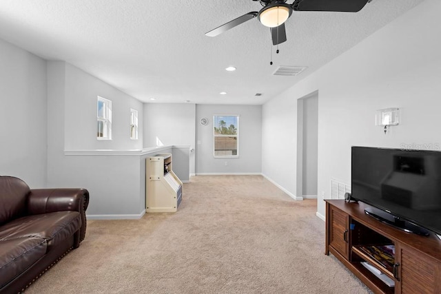 living room featuring light carpet, baseboards, visible vents, a textured ceiling, and recessed lighting