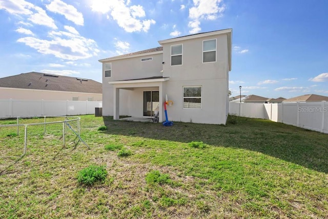 back of property with a fenced backyard, a lawn, and stucco siding