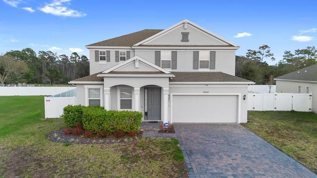 traditional-style house featuring a gate, fence, decorative driveway, and a front yard