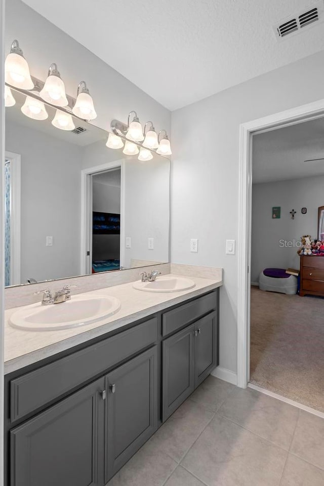 bathroom with double vanity, tile patterned flooring, visible vents, and a sink