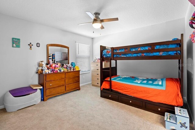 carpeted bedroom featuring a ceiling fan and a textured ceiling