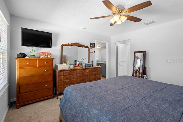 carpeted bedroom featuring ceiling fan, ensuite bath, and visible vents